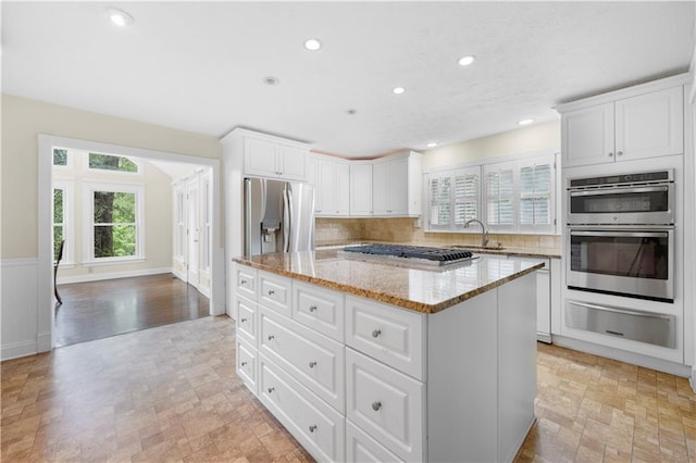 5065 Nesbit Ferry Ln, Atlanta, GA 30350 - kitchen with a warming drawer, stainless steel appliances, a center island, light stone counters, and white cabinetry