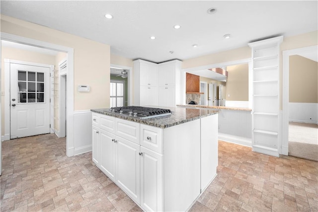 5065 Nesbit Ferry Ln, Atlanta, GA 30350 - kitchen with wainscoting, stainless steel gas cooktop, a center island, white cabinetry, and dark stone countertops