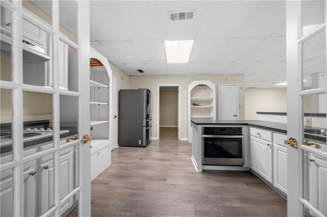 5065 Nesbit Ferry Ln, Atlanta, GA 30350 - kitchen featuring stainless steel appliances, dark wood finished floors, dark countertops, white cabinetry, and a drop ceiling