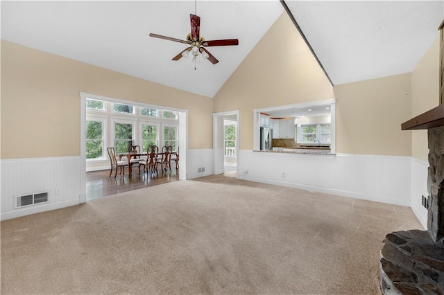 5065 Nesbit Ferry Ln, Atlanta, GA 30350 - living room with a wainscoted wall, light colored carpet, a fireplace with raised hearth, ceiling fan, and high vaulted ceiling