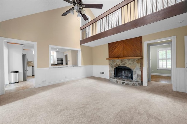 5065 Nesbit Ferry Ln, Atlanta, GA 30350 - unfurnished living room featuring light carpet, a ceiling fan, a towering ceiling, a fireplace, and wainscoting