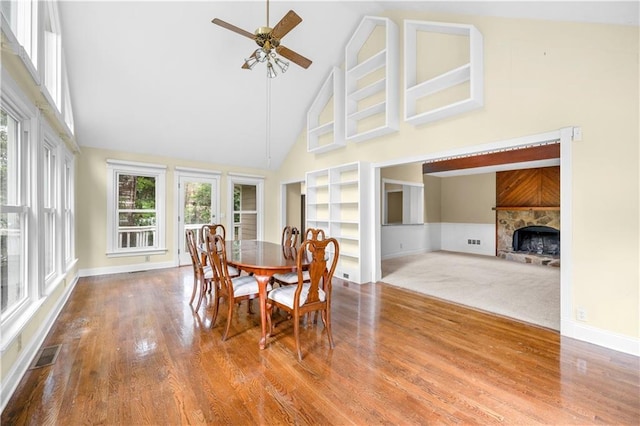 5065 Nesbit Ferry Ln, Atlanta, GA 30350 - dining area with high vaulted ceiling, ceiling fan, wood finished floors, a tiled fireplace, and built in shelves