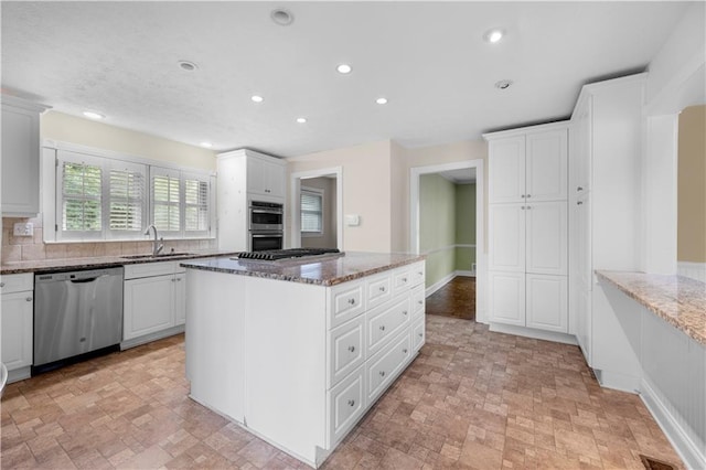 5065 Nesbit Ferry Ln, Atlanta, GA 30350 - kitchen featuring appliances with stainless steel finishes, a kitchen island, dark stone counters, stone finish floors, and recessed lighting