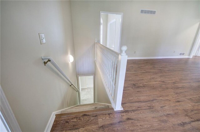 staircase with visible vents, baseboards, and wood finished floors