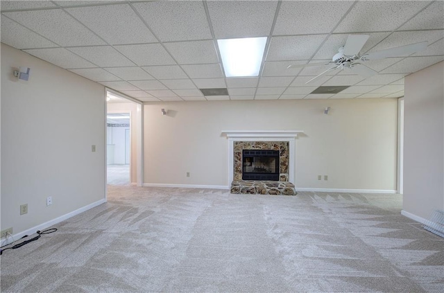 unfurnished living room with a fireplace with raised hearth, carpet, a ceiling fan, and baseboards