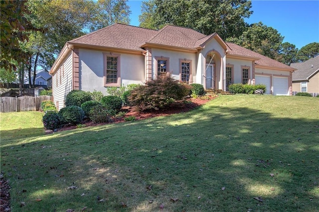 view of front facade featuring a front lawn, an attached garage, fence, and stucco siding