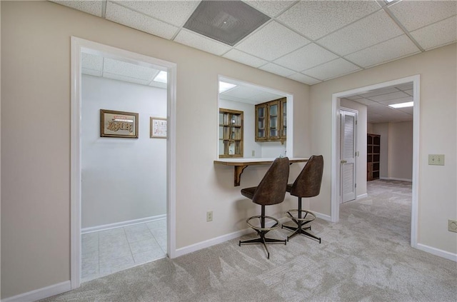 corridor with carpet, a drop ceiling, and baseboards