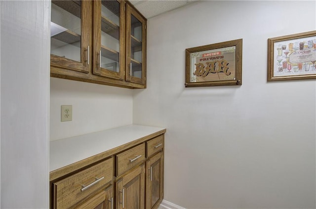 interior space featuring brown cabinets, glass insert cabinets, and light countertops