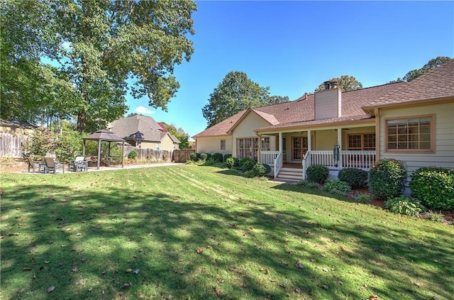 view of yard featuring covered porch, fence, and a gazebo