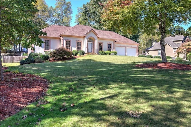 mediterranean / spanish-style home featuring a garage, fence, a front lawn, and stucco siding