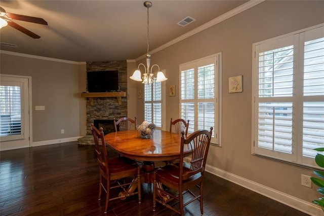 dining room featuring a stone fireplace, ornamental molding, and dark hardwood / wood-style floors