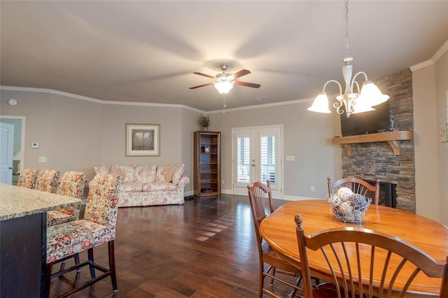 dining space featuring a fireplace, crown molding, dark wood-type flooring, and ceiling fan with notable chandelier