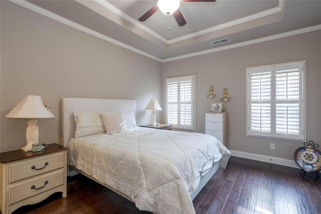 bedroom with multiple windows, ornamental molding, dark wood-type flooring, and a tray ceiling