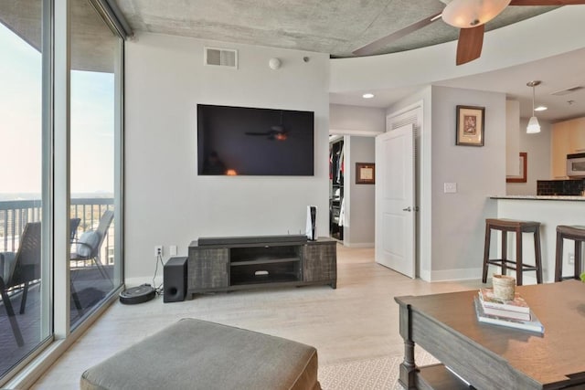 living room with ceiling fan, floor to ceiling windows, and light wood-type flooring