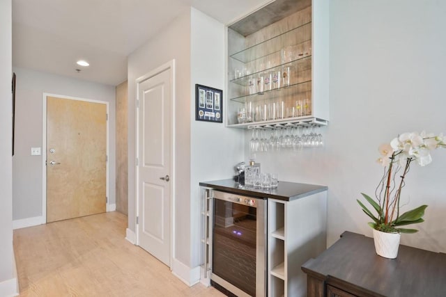 bar with wine cooler and light hardwood / wood-style flooring