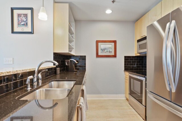 kitchen with sink, tasteful backsplash, decorative light fixtures, appliances with stainless steel finishes, and light wood-type flooring