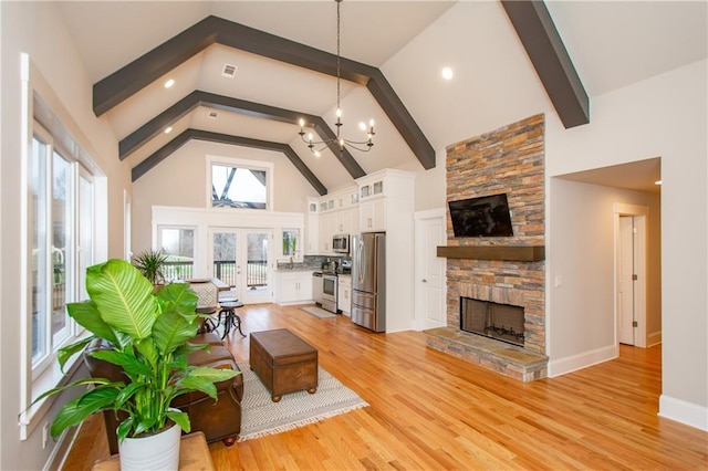 living room with high vaulted ceiling, a chandelier, a fireplace, light hardwood / wood-style floors, and beamed ceiling