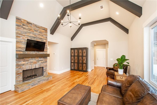 living room with beam ceiling, a notable chandelier, a stone fireplace, and wood-type flooring