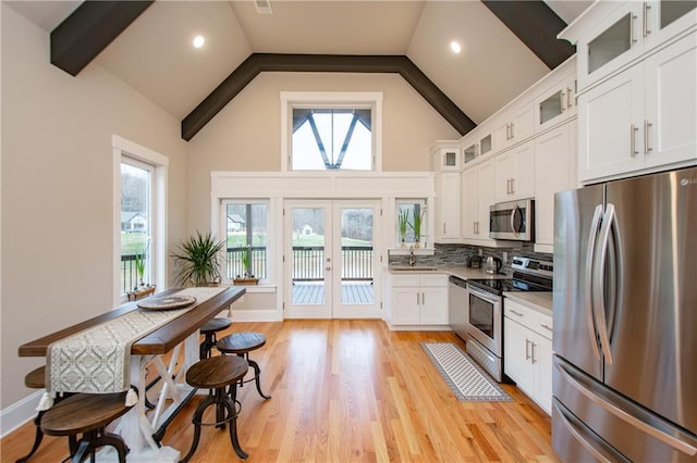 kitchen with stainless steel appliances, a wealth of natural light, white cabinets, and light wood-type flooring