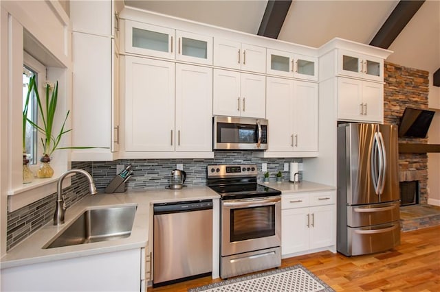 kitchen featuring appliances with stainless steel finishes, white cabinetry, sink, backsplash, and light wood-type flooring