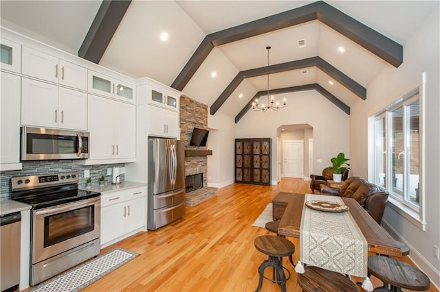 kitchen with white cabinetry, a notable chandelier, a fireplace, and appliances with stainless steel finishes