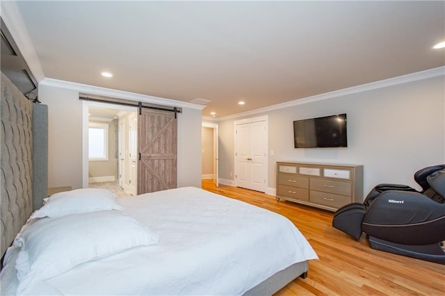 bedroom featuring crown molding, a barn door, and light wood-type flooring