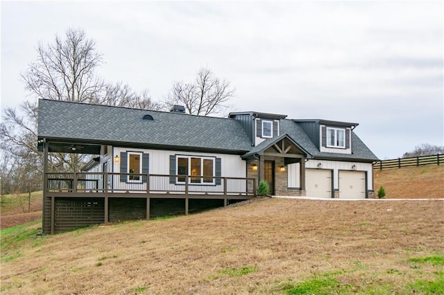 view of front facade with a garage, a wooden deck, and a front lawn