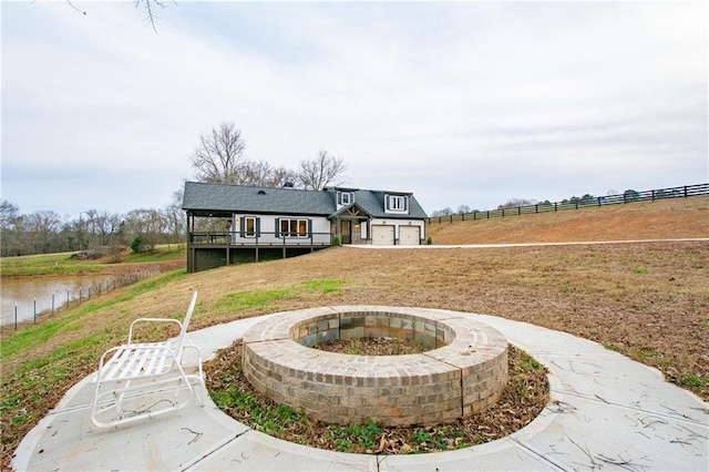 rear view of house featuring a water view, a fire pit, and a lawn