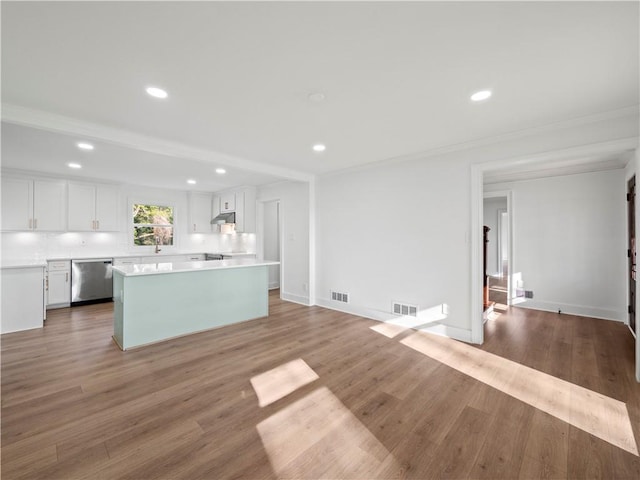 kitchen with under cabinet range hood, stainless steel dishwasher, light countertops, and white cabinetry
