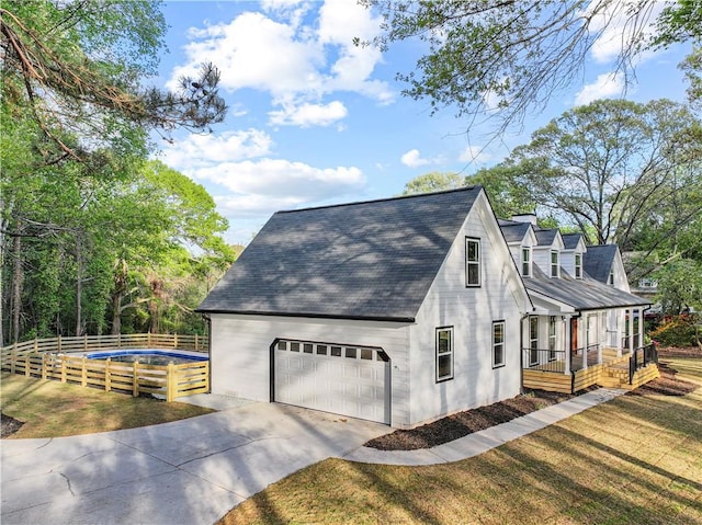 view of side of home with roof with shingles, a yard, concrete driveway, and fence