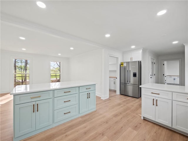 kitchen with stainless steel fridge with ice dispenser, recessed lighting, light countertops, white cabinets, and light wood finished floors