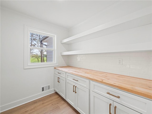 bar with visible vents, baseboards, ornamental molding, light wood-type flooring, and backsplash