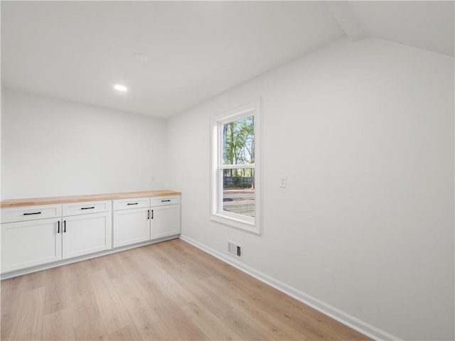 spare room featuring visible vents, baseboards, lofted ceiling with beams, light wood-type flooring, and recessed lighting