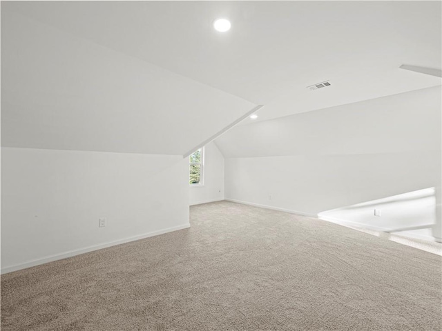 additional living space featuring carpet, baseboards, vaulted ceiling, and visible vents