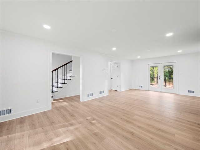 unfurnished living room featuring french doors, visible vents, light wood finished floors, and stairway