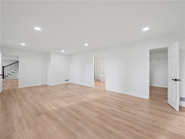 interior space featuring baseboards, light wood finished floors, recessed lighting, and stairs