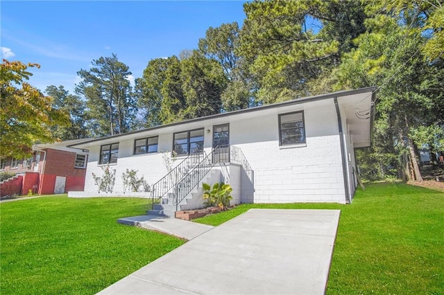 ranch-style house featuring concrete driveway, brick siding, and a front yard