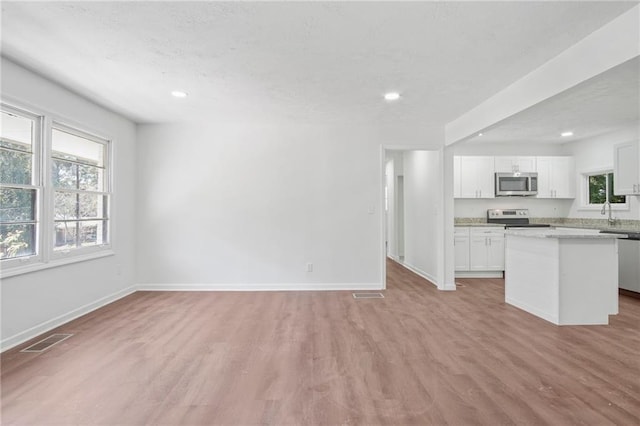 unfurnished living room with light wood-type flooring, visible vents, baseboards, and recessed lighting