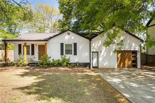view of front of home with a garage, a porch, fence, and concrete driveway