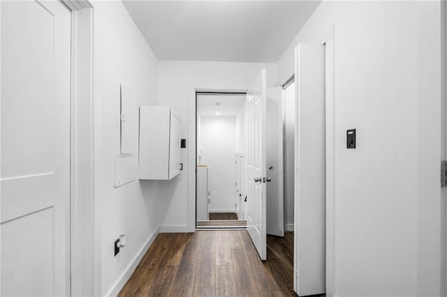 hall featuring dark wood-style flooring and baseboards