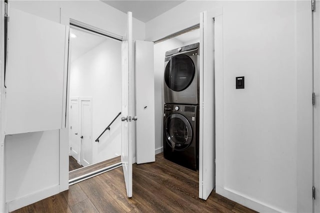 laundry area with stacked washer / dryer, laundry area, baseboards, and dark wood-style floors