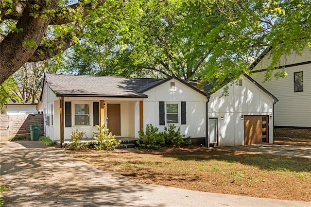 view of front of property featuring covered porch, roof with shingles, fence, an attached garage, and concrete driveway