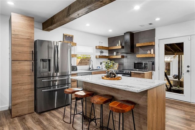 kitchen with visible vents, open shelves, wall chimney range hood, appliances with stainless steel finishes, and a kitchen bar