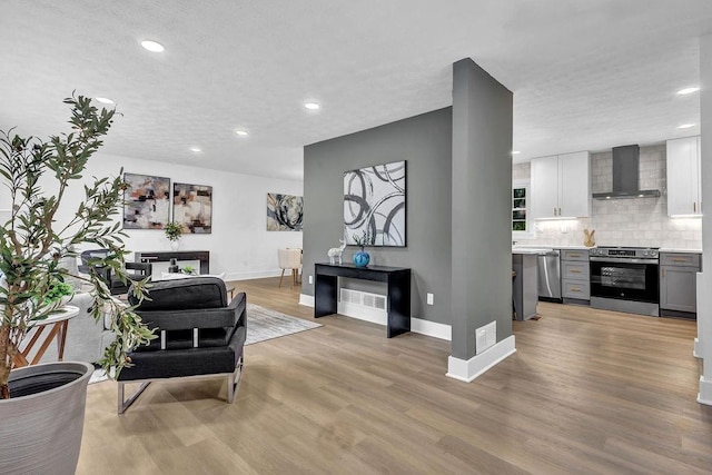 living area with baseboards, recessed lighting, and light wood-type flooring