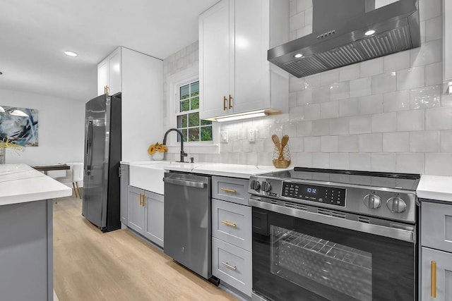 kitchen with gray cabinetry, stainless steel appliances, backsplash, and range hood