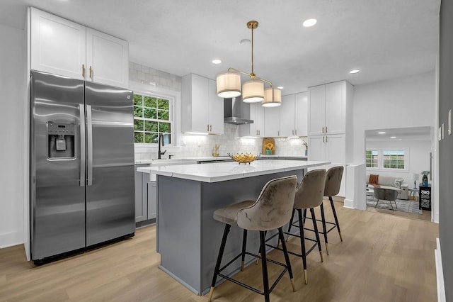 kitchen featuring tasteful backsplash, stainless steel refrigerator with ice dispenser, a kitchen island, and light wood finished floors