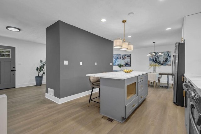 kitchen featuring visible vents, light wood finished floors, freestanding refrigerator, and gray cabinets