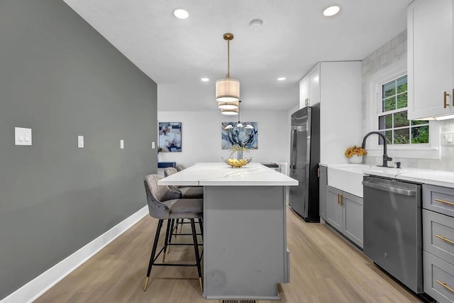 kitchen featuring recessed lighting, gray cabinets, light wood-type flooring, a kitchen island, and appliances with stainless steel finishes