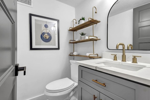 bathroom with vanity, toilet, and visible vents
