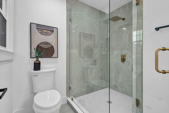 bathroom featuring toilet, a stall shower, and baseboards